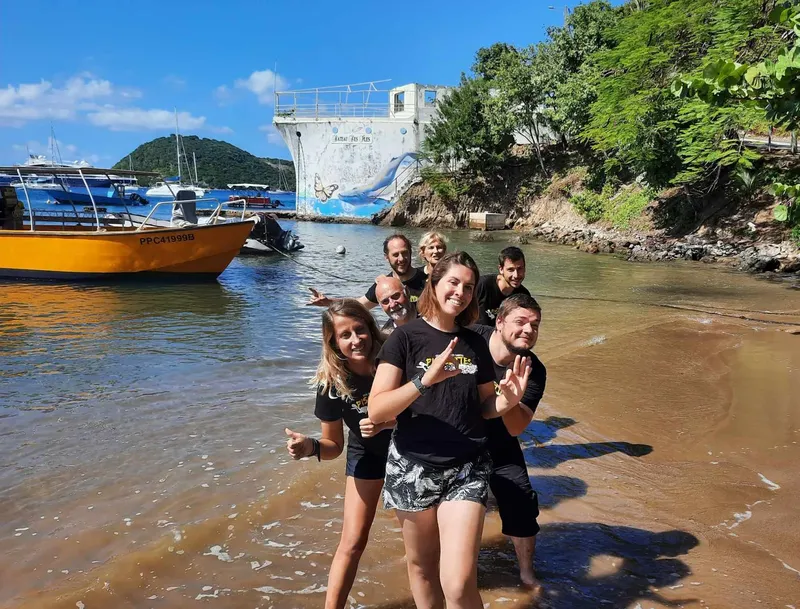 Groupe de personnes souriantes près d'un bateau et d'un bâtiment