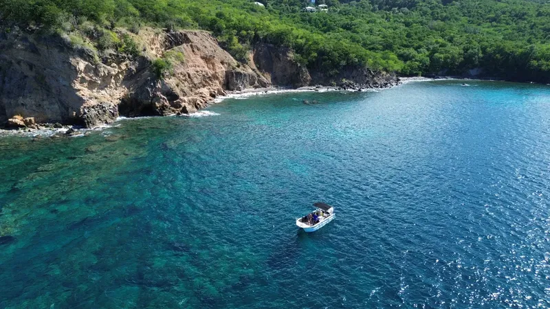 Bateau de plongée navigue dans une baie turquoise avec des falaises