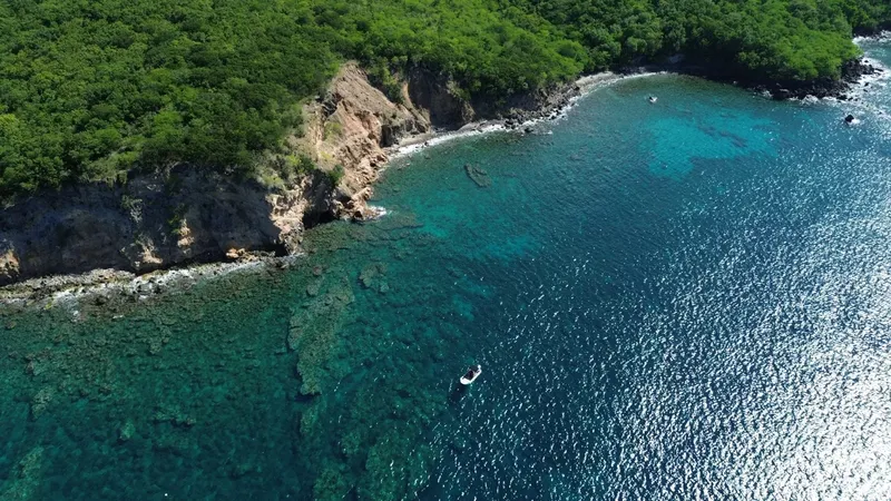 Vue aérienne d'une côte rocheuse avec un bateau en mer turquoise