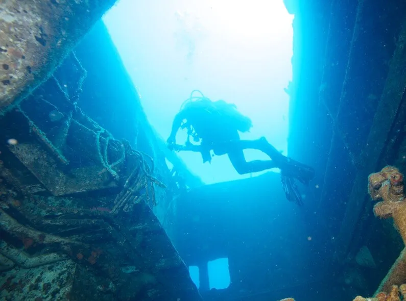 Plongeur explorant l'intérieur d'une épave sous-marine éclairée