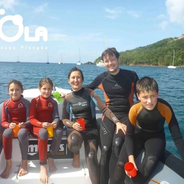 Groupe de personnes souriantes en combinaison de plongée sur un bateau