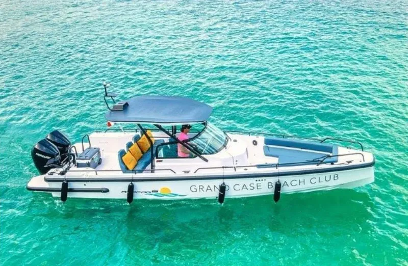 Bateau à moteur blanc et bleu naviguant sur une eau turquoise claire