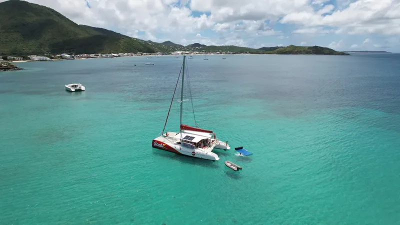 Catamaran blanc et rouge amarré dans une eau turquoise claire