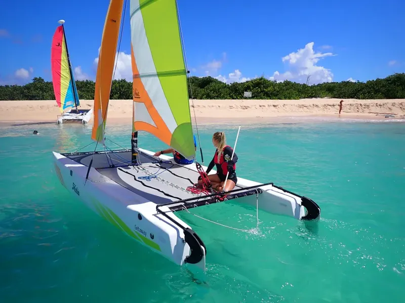Deux personnes naviguent sur un catamaran dans une eau turquoise