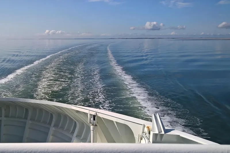Vue depuis un bateau en mer, sillage blanc sur l'eau bleue
