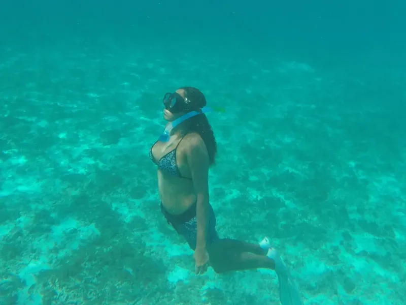 Plongeuse en apnée, regardant vers le haut dans une eau turquoise claire