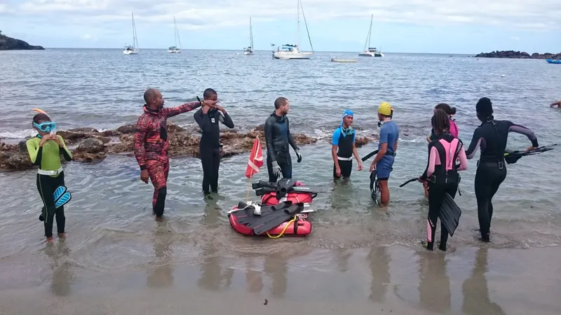 Groupe de plongeurs en combinaison sur une plage, préparation plongée