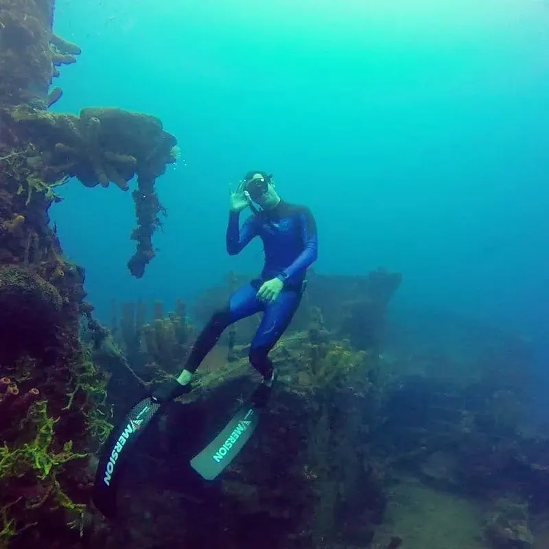 Plongeur en combinaison noire nageant dans une eau turquoise claire