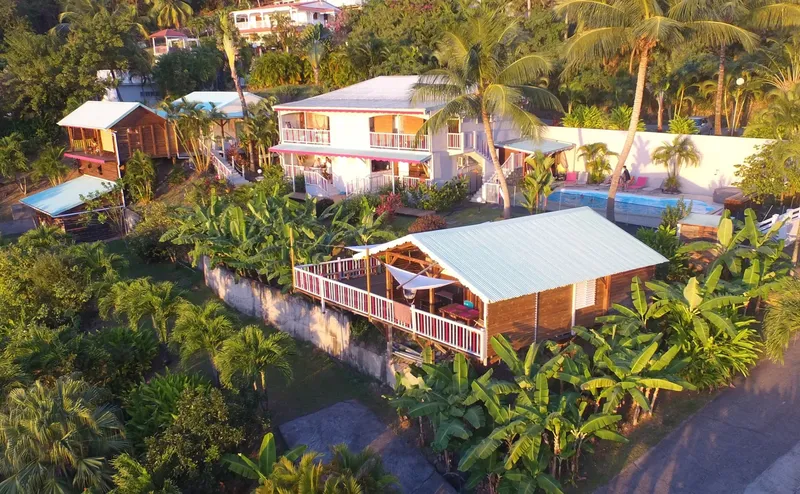 Vue aérienne de bâtiments avec terrasse, végétation tropicale et piscine