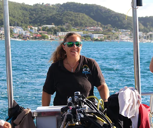 Femme souriante sur un bateau de plongée avec du matériel