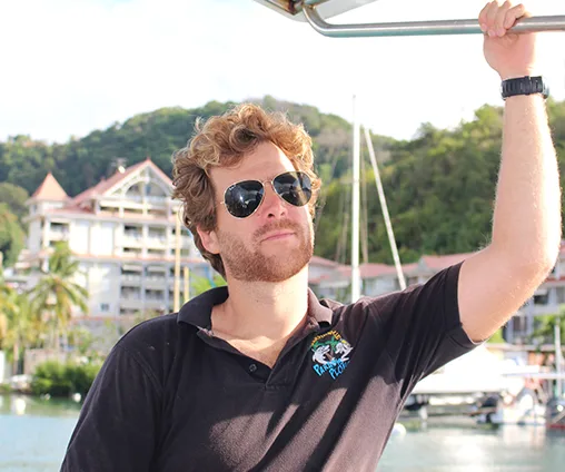 Jeune homme souriant avec des lunettes de soleil sur un bateau
