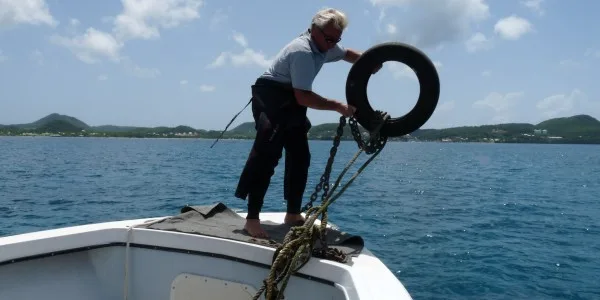 Homme manipulant une bouée noire sur le pont d'un bateau en mer