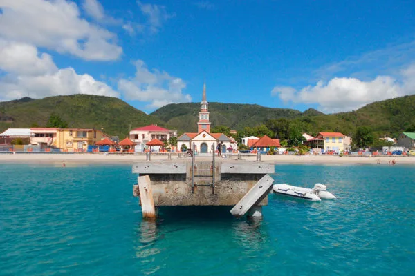 Vue d'une plage avec un ponton, des bâtiments colorés et des personnes