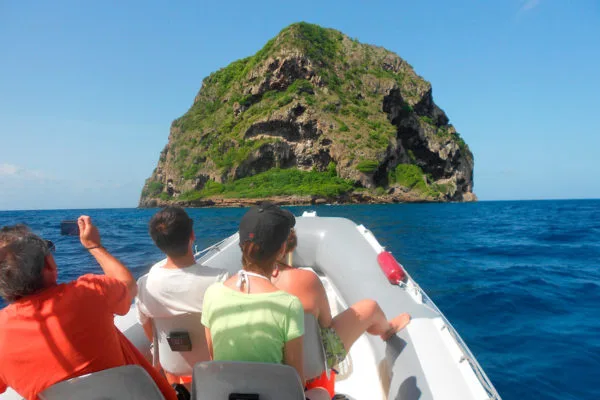 Personnes à bord d'un bateau se dirigeant vers une île rocheuse