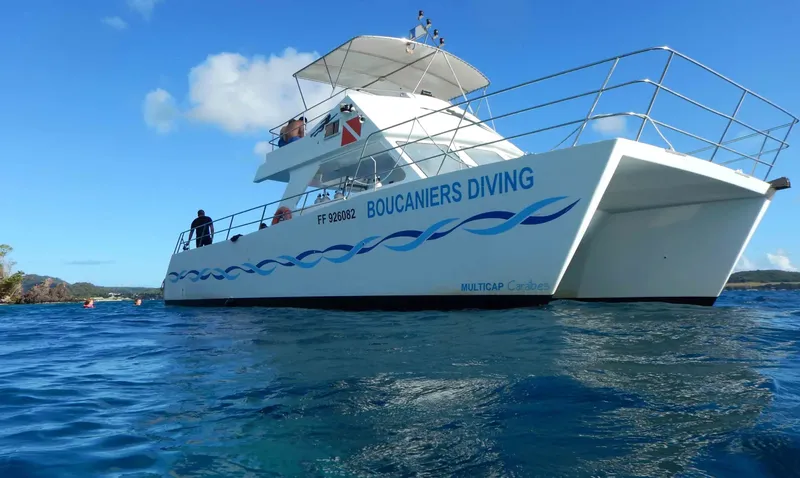 Catamaran blanc avec des plongeurs à bord sur une mer bleue