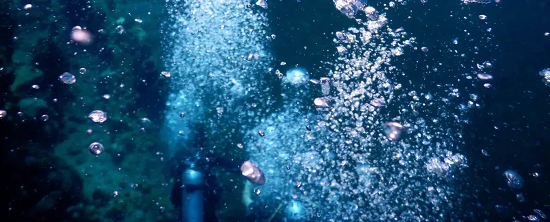 Plongeur dans l'eau avec de nombreuses bulles lumineuses autour