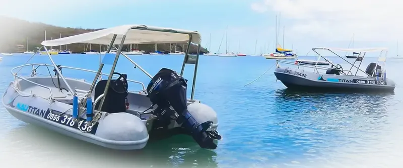 Deux bateaux semi-rigides amarrés dans une baie ensoleillée avec des voiliers