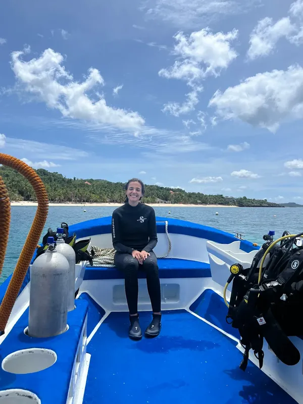 Plongeuse assise dans un bateau de plongée bleu et blanc