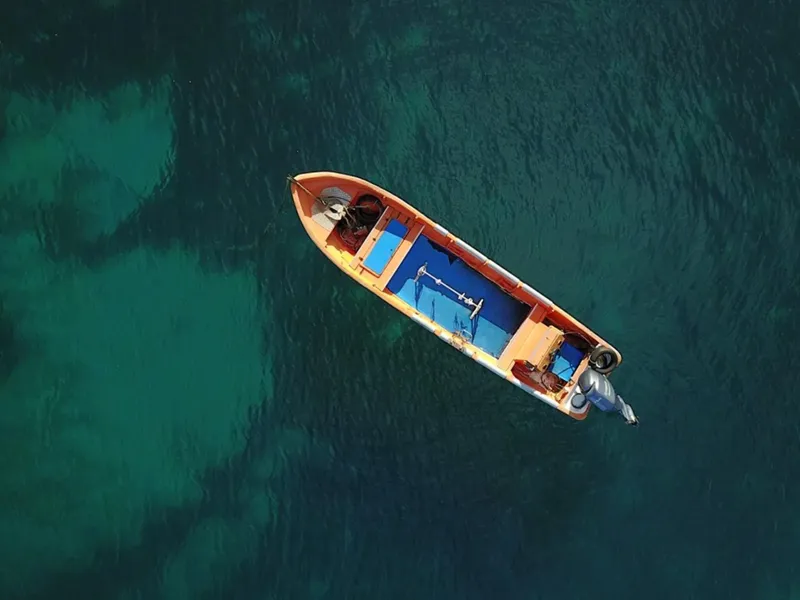 Bateau orange naviguant sur une mer turquoise vue d'en haut