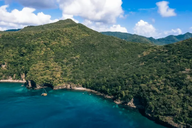 Crique turquoise bordée de végétation luxuriante et de montagnes verdoyantes