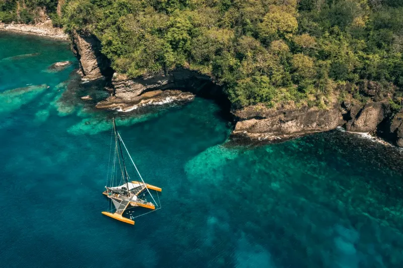 Catamaran de plongée amarré dans une crique turquoise bordée de falaises