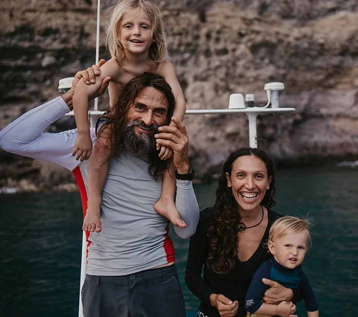 Famille souriante près d'un bateau, en bord de mer ensoleillé