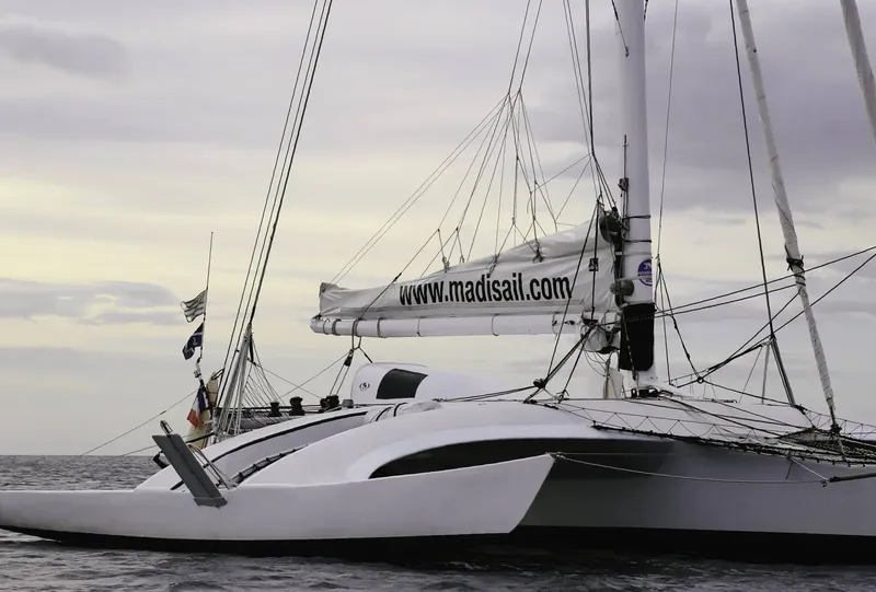 Catamaran blanc avec voile enroulée et adresse web visible