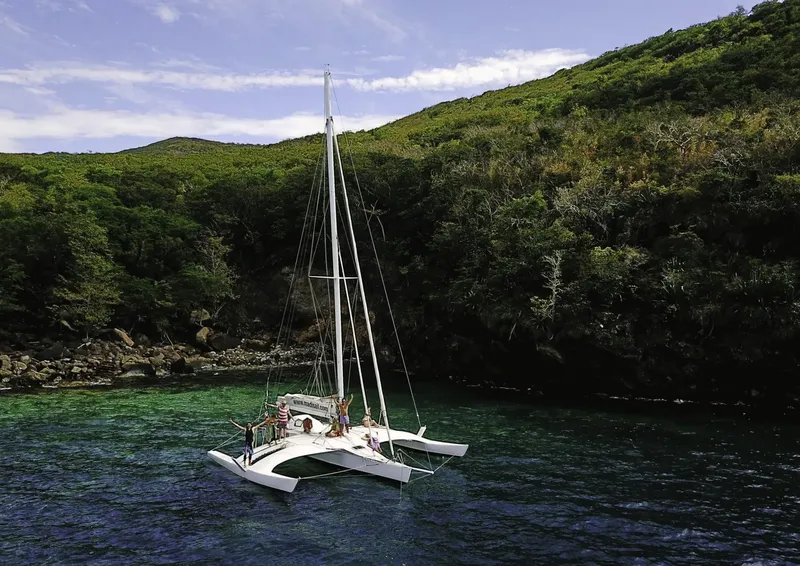 Catamaran blanc amarré dans une baie avec des personnes à bord