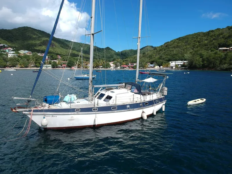 Voilier amarré dans une baie tropicale avec des collines verdoyantes