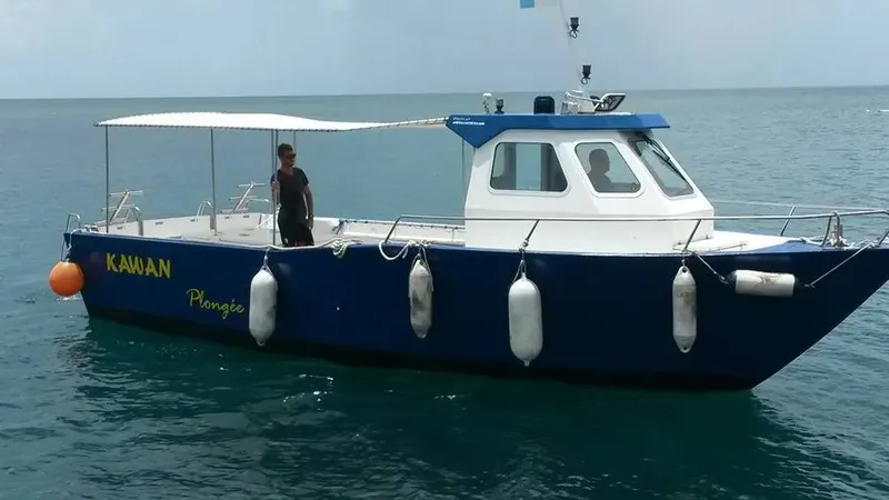 Bateau de plongée bleu et blanc avec des passagers sur l'eau calme