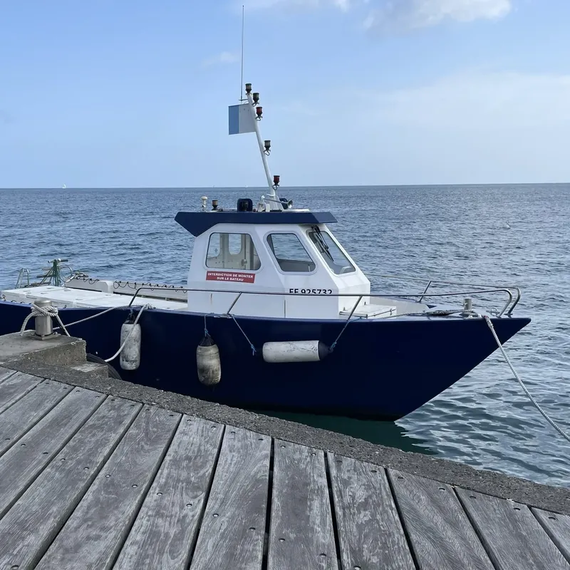 Bateau de plongée amarré à un ponton en bois, mer calme
