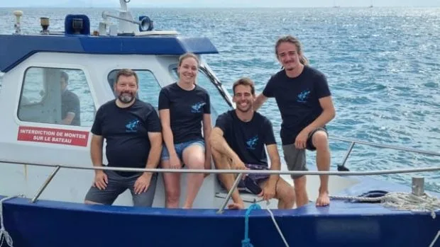 Quatre personnes souriantes posent sur la proue d'un bateau de plongée