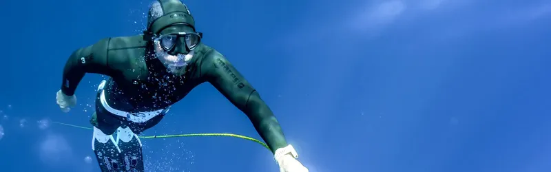 Apnéiste en combinaison sombre nageant en eaux bleues, masque et tuba