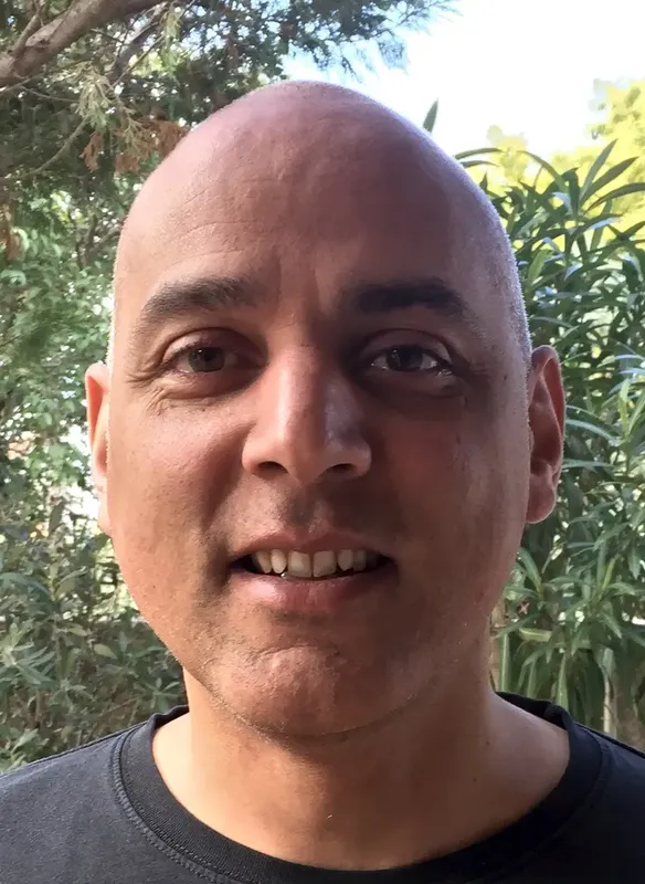 Portrait d'un homme chauve souriant, regardant vers l'avant, lumière naturelle