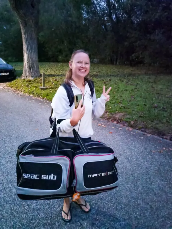 Femme souriante tenant un grand sac de matériel de plongée
