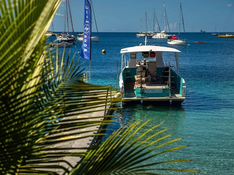 Bateau de plongée turquoise amarré à un ponton en eau turquoise