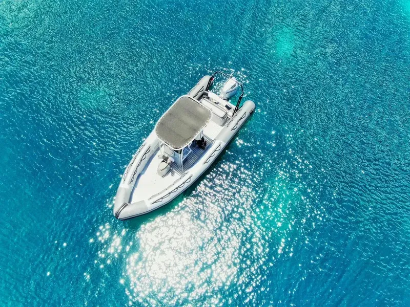 Bateau semi-rigide blanc naviguant sur une mer turquoise et calme