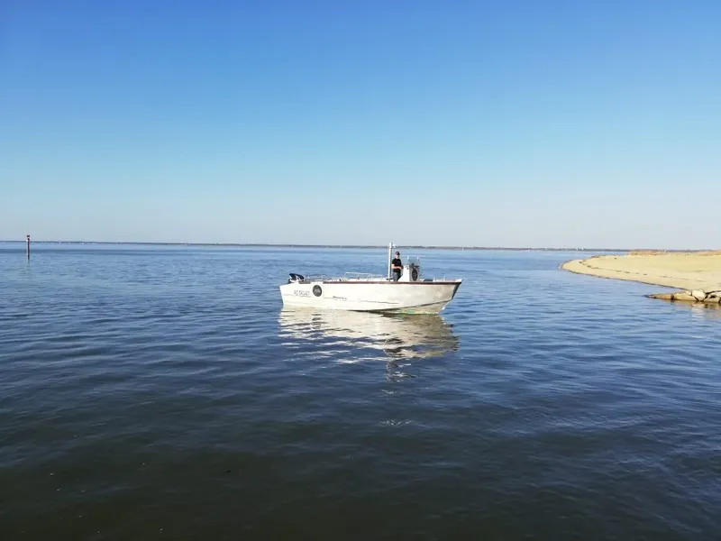 Petit bateau blanc navigue sur une mer calme sous ciel bleu