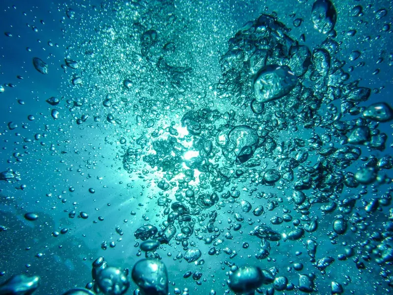Bulles remontant vers la surface en eau turquoise claire