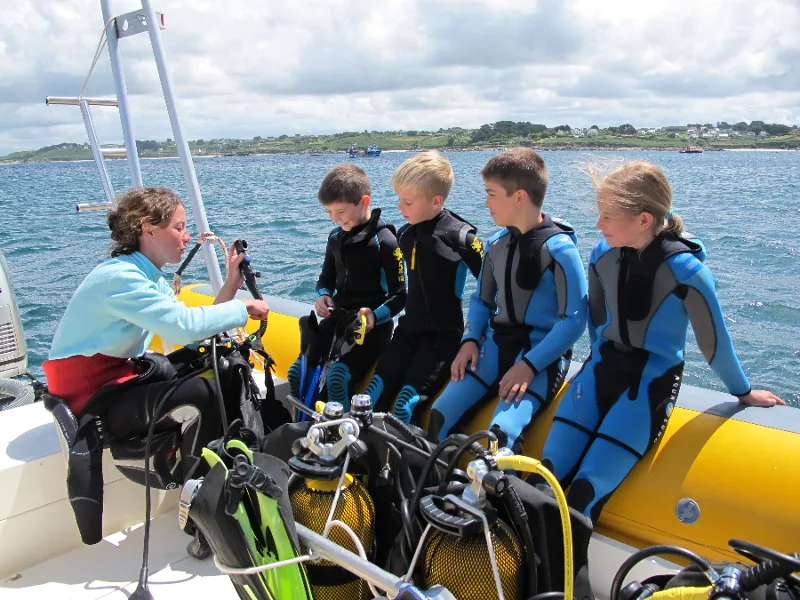 Instructeur expliquant l'équipement de plongée à des jeunes stagiaires sur un bateau