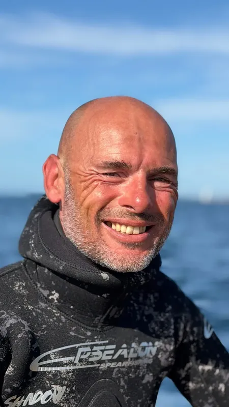 Homme souriant portant une combinaison de plongée, regardant vers l'avant