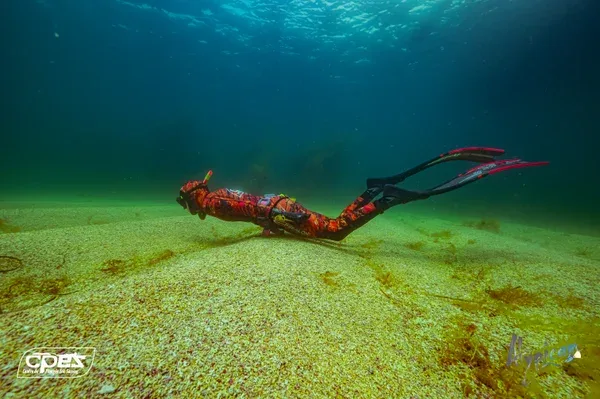 Apnéiste en mouvement sous l'eau sur fond sablonneux et lumineux