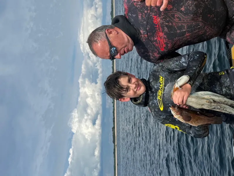 Deux personnes souriantes en combinaison de plongée près de l'eau