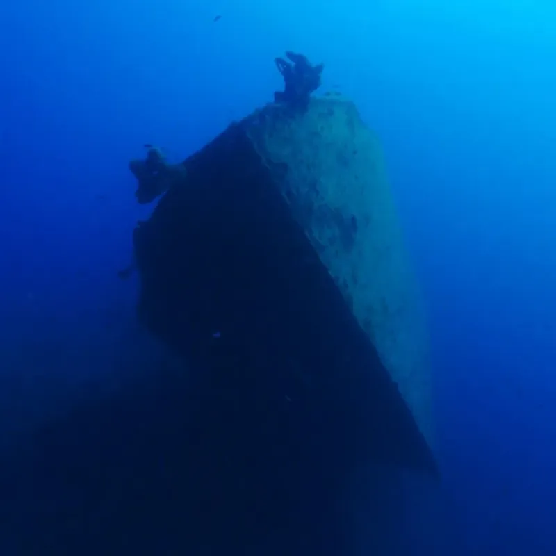 Épave de bateau submergée dans une eau bleue profonde et claire