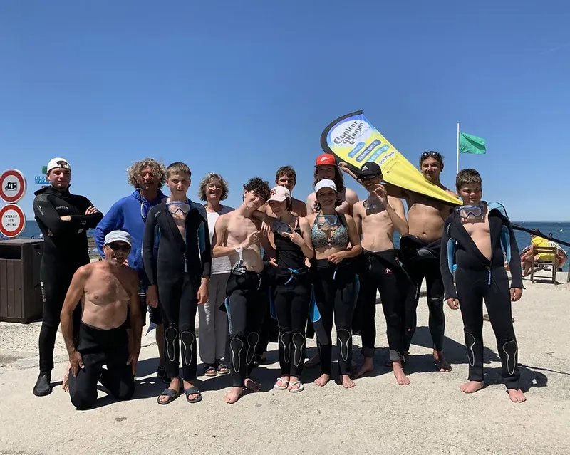Groupe de personnes souriantes sur une plage avec un drapeau