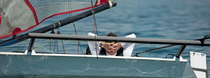 Homme sur un bateau de sport, les yeux couverts par sa main