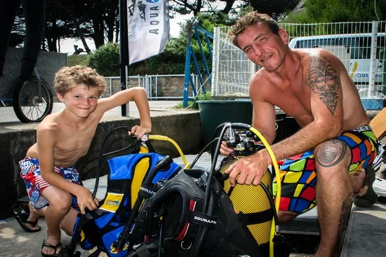 Un enfant et un homme sourient avec du matériel de plongée