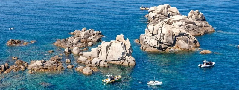 Archipel rocheux en mer avec quelques bateaux de plaisance turquoise