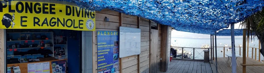 Façade d'un centre de plongée avec matériel, ponton et bateaux amarrés