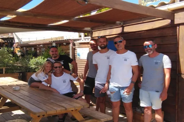 Groupe de personnes souriantes posant devant une structure en bois